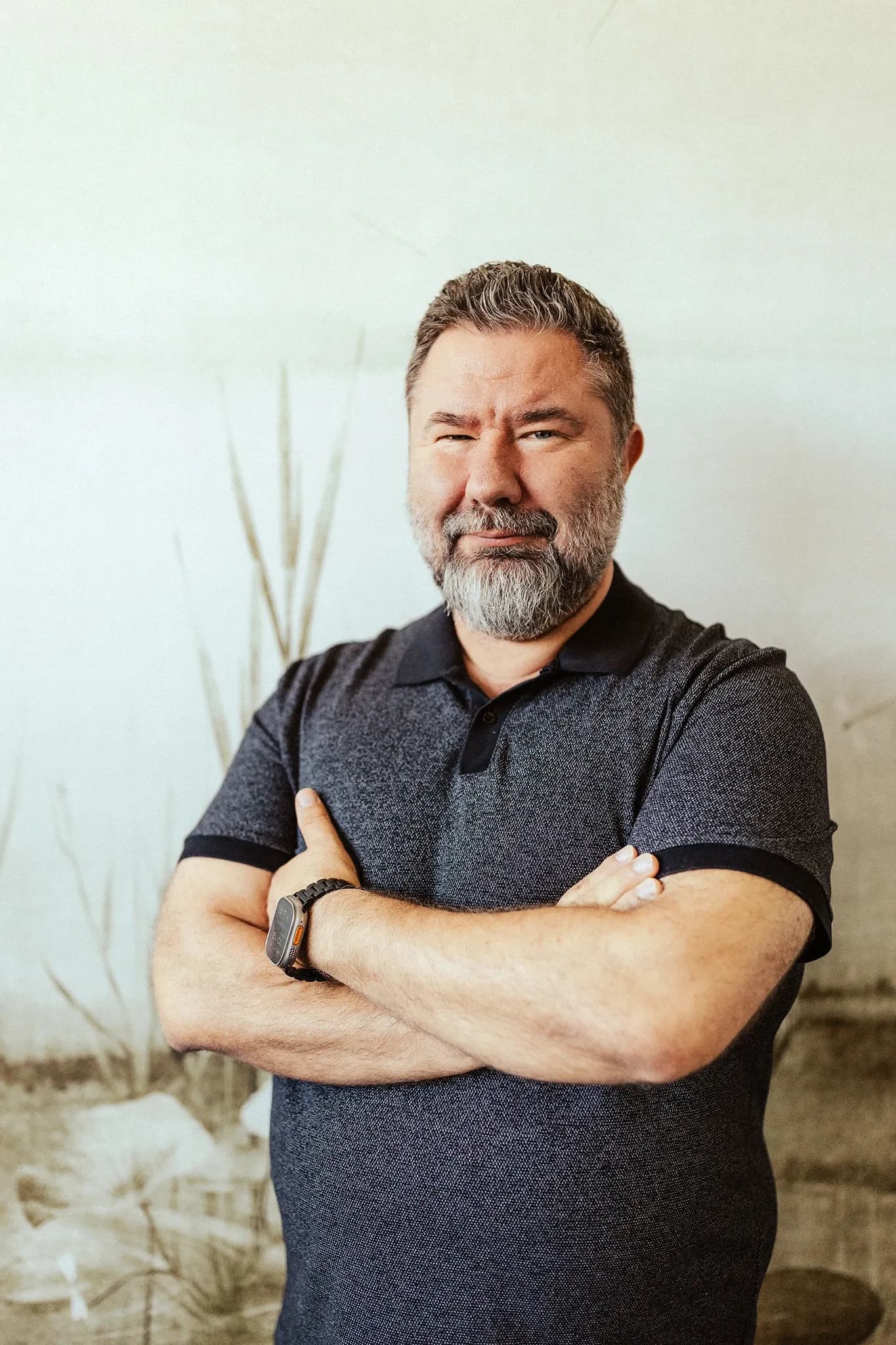 Petr Kohout v tmavém tričku se založenýma rukama ve své pracovně